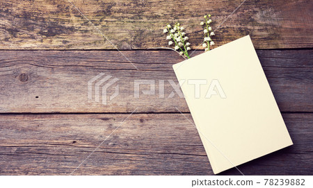 notebook with blank white sheets and a bouquet of blooming lilies of the valley on a wooden table from gray boards 78239882