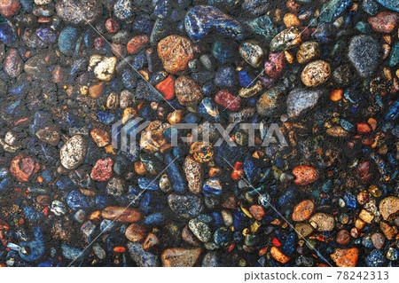 Dark texture of asphalt mixed with many small multi-colored stones 78242313