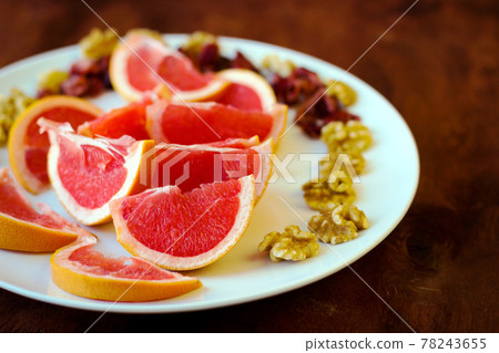 Wonderful vegan food: grapefruit sliced with slices, walnut kernels, dried cranberries stand on a white plate Wonderful vegan food: grapefruit sliced with slices, walnut kernels, dried cranberries stand on a white plate 78243655