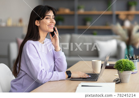 Smiling lady working and talking on phone at home 78245214