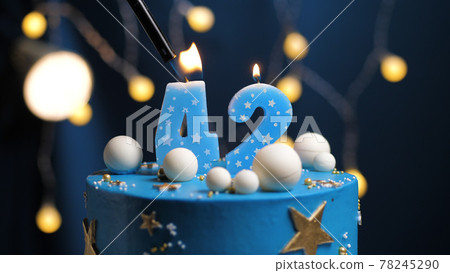 Birthday cake number 42 stars sky and moon concept, blue candle is fire by lighter. Copy space on right side of screen. Close-up 78245290