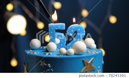 Birthday cake number 52 stars sky and moon concept, blue candle is fire by lighter. Copy space on right side of screen. Close-up 78245301