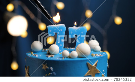 Birthday cake number 77 stars sky and moon concept, blue candle is fire by lighter. Copy space on right side of screen. Close-up Birthday cake number 77 stars sky and moon concept, blue candle is fire by lighter. Copy space on right side of screen. Close-up 78245332
