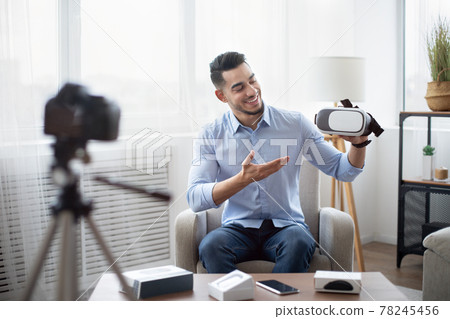 Tech product review. Male vlogger presenting VR headset, recording video about innovative device for technology blog Tech product review. Male vlogger presenting VR headset, recording video about innovative device for technology blog 78245456