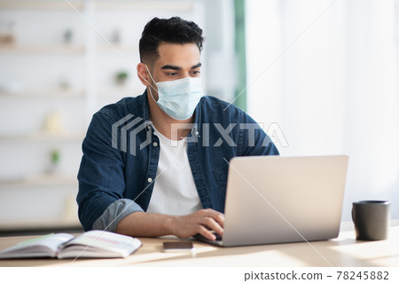 Arab man in protective face mask using laptop Arab man in protective face mask using laptop 78245882