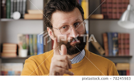 Man threatens with his finger. Serious frowning bearded man in glasses in office or apartment room looking at camera and points menacingly with his index finger. Close up Man threatens with his finger. Serious frowning bearded man in glasses in office or apartment room looking at camera and points menacingly with his index finger. Close up 78245983