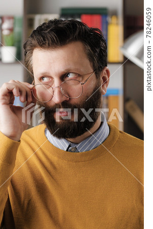 Skepticism, sarcasm emotion. Bearded man in glasses in office or apartment room expressing his skeptical attitude and discontent with his look. Close up 78246059