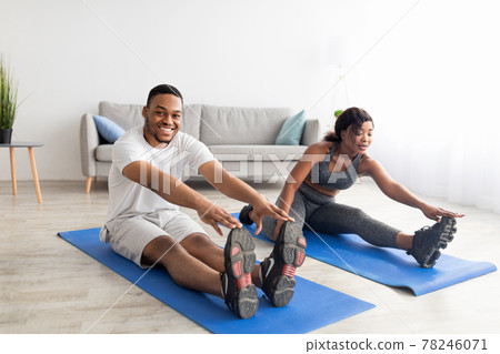 Young African American couple stretching on yoga mats, making domestic workout, doing flexibility exercises at home 78246071
