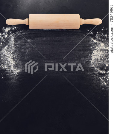 Wooden rolling pin in hands and flour. Bakery on a black stone background. Wooden rolling pin in hands and flour. Bakery on a black stone background. 78249963