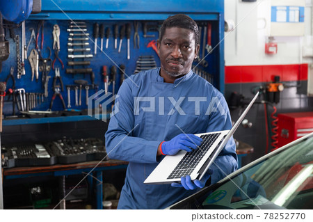 Mechanic using a laptop to work in service 78252770