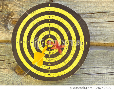 Large playable yellow and black dartboard or darts in the bar against the background of a wooden wall 78252809