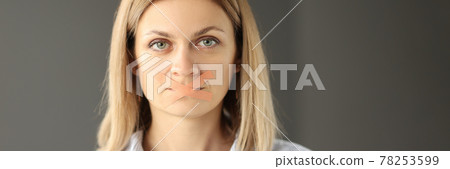 Portrait of woman with tape taped mouth 78253599
