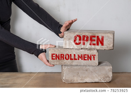 Open Enrollment concept. Stack of white bricks on a wooden table Open Enrollment concept. Stack of white bricks on a wooden table 78253925