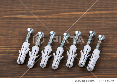 Screws with dowels on a wooden texture table Screws with dowels on a wooden texture table 78253926