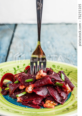 On a bright ethnic plate is a vegetarian lean beet salad, green shnit-onion, gritsy nut. Top view. The concept of simple healthy food 78255105
