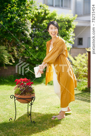 Middle woman watering flowers in the garden 78255454