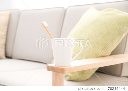 沙發扶手上放著一個帶牙刷的杯子 78256444