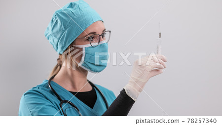 Female doctor prepares a syringe with the new Corona vaccine Female doctor prepares a syringe with the new Corona vaccine 78257340
