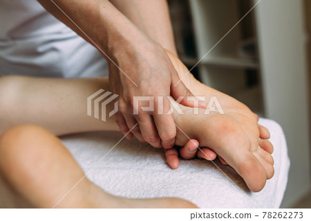 The masseur gives a massage to the female feet at the spa. 78262273