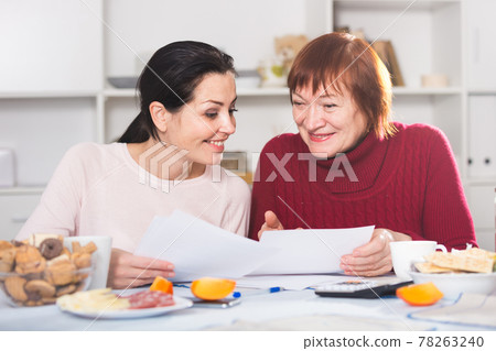 Happy women with documents sitting at table Happy women with documents sitting at table 78263240