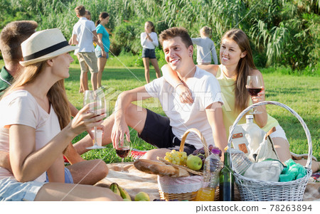 Happy young people on picnic in park and kids playing Happy young people on picnic in park and kids playing 78263894