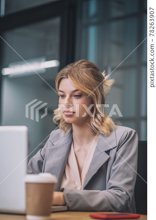 Beautiful young woman at table with coffee and laptop Beautiful young woman at table with coffee and laptop 78263907