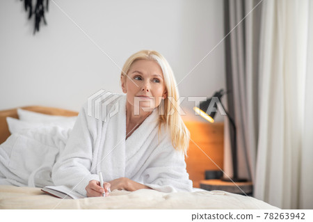 A cute woman lying on the bed and making notes A cute woman lying on the bed and making notes 78263942