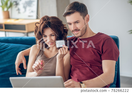 Young couple siting on the sofa and choosing products online Young couple siting on the sofa and choosing products online 78266222
