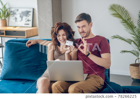 Young couple siting on the sofa and choosing products online Young couple siting on the sofa and choosing products online 78266225