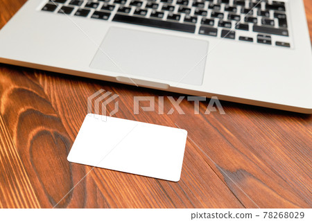 The card mock up, copy space - lies in front of a laptop on a wooden background. The card mock up, copy space - lies in front of a laptop on a wooden background. 78268029