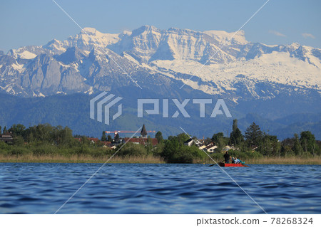 Church tower of Wetzikon and snow capped mountains. 78268324