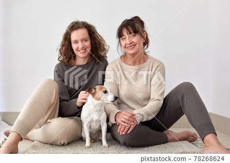 Smiling mother and daughter with dog at home Smiling mother and daughter with dog at home 78268624