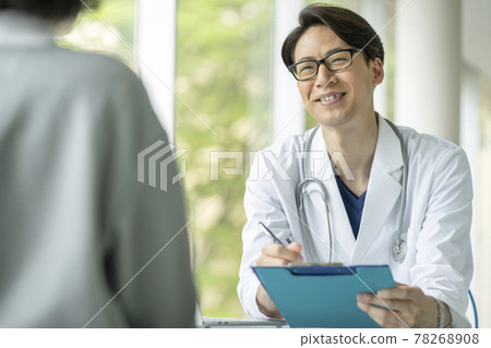 Male doctor examining with a smile Male doctor examining with a smile 78268908
