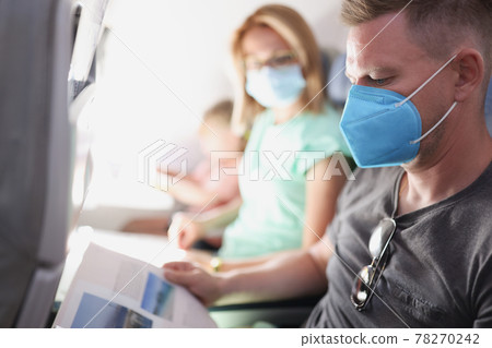 Young family is flying in airplane wearing protective medical mask 78270242