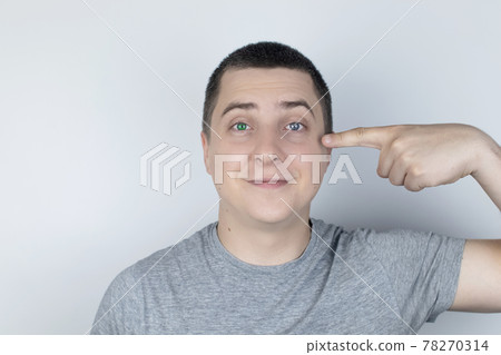 A man with different color eyes looks into the frame. The right eye is blue and the left is green. Heterochromia. Gene mutation. Multi-colored eyes. 78270314