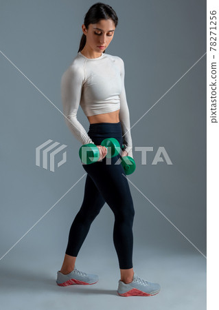 Girl performing upper body workout with dumbbells in studio 78271256
