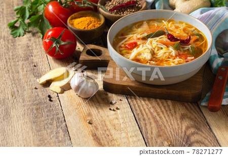 Tukpa soup of Indian cuisine. Hot noodle soup with chicken, ginger, cilantro and spices on a deyven wooden table. Copy space. 78271277