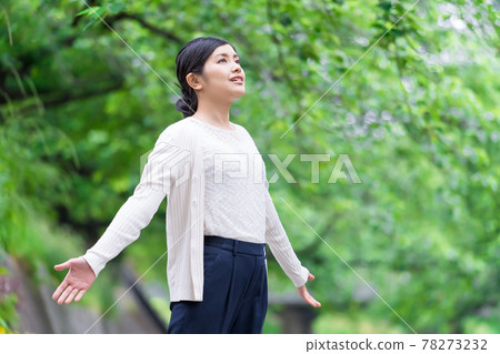 A business woman taking a deep breath with her hands open in the fresh green A business woman taking a deep breath with her hands open in the fresh green 78273232