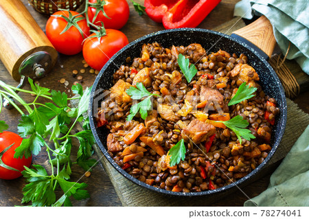 Indian cuisine dish. Traditional indian spicy green lentils with meat, spices, herbs in a cast-iron frying pan on a wooden table. 78274041