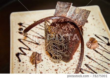 Piece of chocolate cake decorated with chocolate and caramel Piece of chocolate cake decorated with chocolate and caramel 78275001