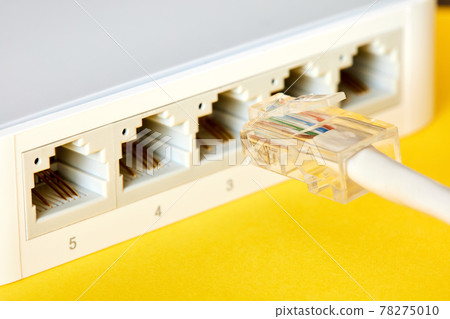 Ethernet cables connected to Desktop Switch or routerboard on a yellow background. Close-up, selective focus 78275010