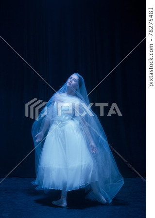 Young graceful balerina in image of ghost bride in art performance isolated on dark background in neon light. 78275481