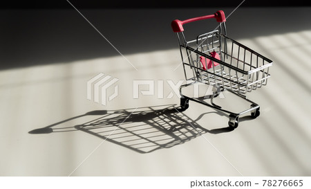 Shopping trolley on white table. Shopping trolley on white table. 78276665