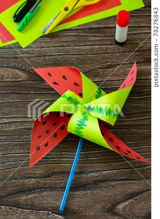 Pinwheel toy. Fun toy watermelon windmill spinning on a wooden table. Children's art project, needlework, crafts for children. 78276843