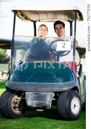 Male and female golf partners using golf cart Male and female golf partners using golf cart 78277836