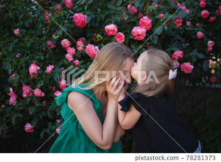 mom hugs her little daughter against the background of a rose bush 78281373