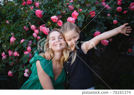 mom hugs her little daughter against the background of a rose bush 78281374