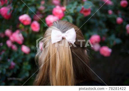 portrait of a little cute girl on the background of bushes of pink roses. back view portrait of a little cute girl on the background of bushes of pink roses. back view 78281422