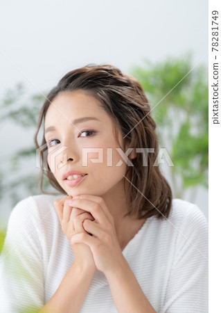Portrait of a smiling young woman surrounded by green and yellow flowers 78281749