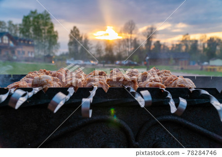 Russia. Leningrad region. May 15, 2021. Cooking meat shish kebab on a cast-iron grill in nature using skewers. 78284746